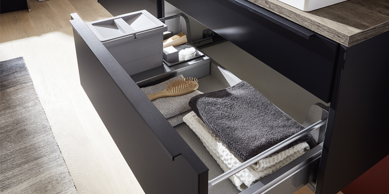 Schwarze Badmöbel sind ein echtes Trendthema. Sehr cool wirken die matten Oberflächen im Kontrast zum Vitrinenschrank Flat mit ultraschmalem Aluminiumrahmen. Runde Abschlusswangen sorgen für einen wohnlichen Charakter. 