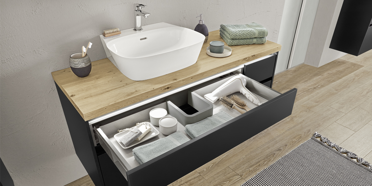 Schwarze Badmöbel sind ein echtes Trendthema. Sehr cool wirken die matten Oberflächen im Kontrast zum Vitrinenschrank Flat mit ultraschmalem Aluminiumrahmen. Runde Abschlusswangen sorgen für einen wohnlichen Charakter. 